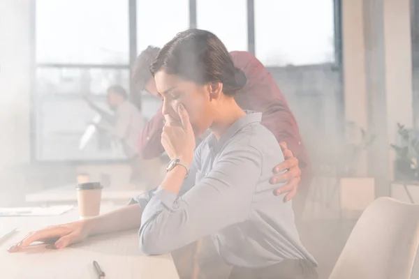 Businesswoman holding nose in office with smoke near coworkers — Stock Photo