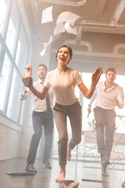 Terrified businesswoman screaming while running near coworkers in office with smoke — Stock Photo