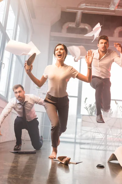 Scared businesswoman screaming while running near coworkers in office with smoke — Stock Photo