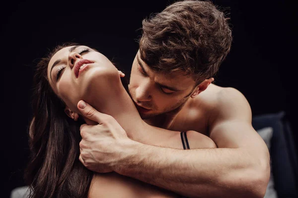 Чоловік цілує красиву сексуальну жінку на шиї ізольовано на чорному — Stock Photo