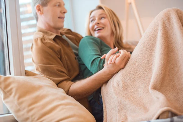 Selective focus of happy couple holding hands while resting under soft fleece blanket — Stock Photo