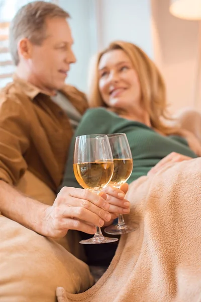 Selective focus of happy couple clinking glasses of white wine — Stock Photo