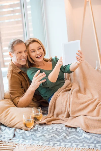 Pareja emocionada usando tableta digital mientras se sienta n piso en el nuevo hogar - foto de stock