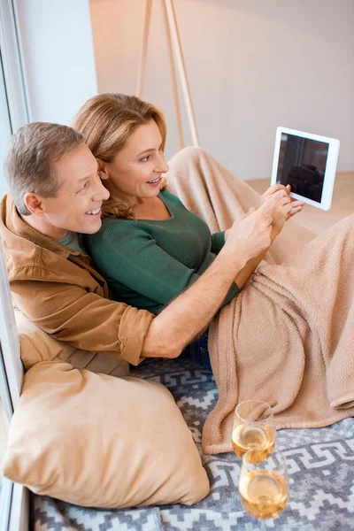 Alegre pareja usando digital tablet mientras sentado en piso en nuevo hogar - foto de stock