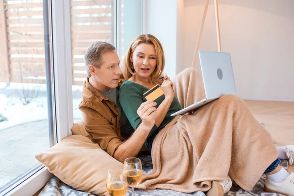 Mann hält Kreditkarte, während er Laptop mit Frau benutzt — Stockfoto