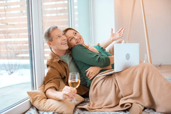 Взволнованная пара сидит на полу в новом доме и с помощью ноутбука — стоковое фото