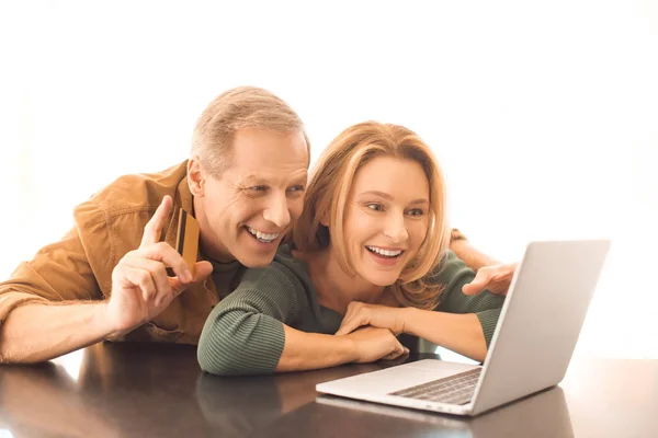 Homme souriant montrant signe d'idée tout en utilisant un ordinateur portable avec femme sur fond blanc — Photo de stock