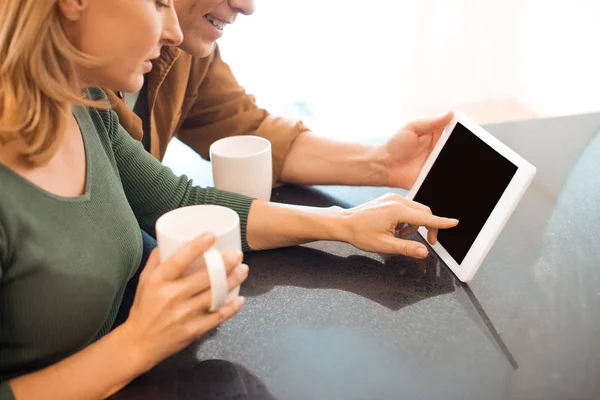 Marido e mulher com xícaras de café usando tablet digital — Fotografia de Stock