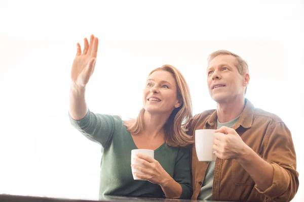 Улыбающаяся женщина, указывающая на руку, стоя рядом с мужем — стоковое фото