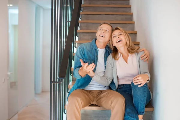 Glückliches Paar umarmt sich im neuen Zuhause auf der Treppe — Stockfoto