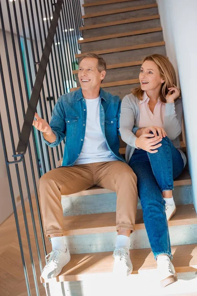 Heureux couple assis sur les escaliers à la nouvelle maison — Photo de stock