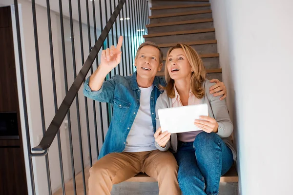 Man pointing with finger while sitting on stairs with digital tablet — Stock Photo