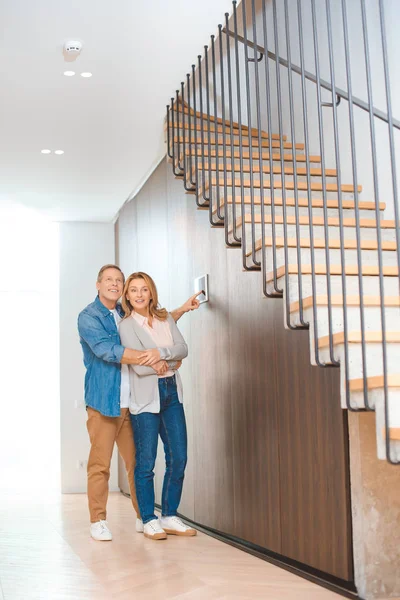 Marido feliz usando painel de controle inteligente casa enquanto abraçando a esposa — Fotografia de Stock