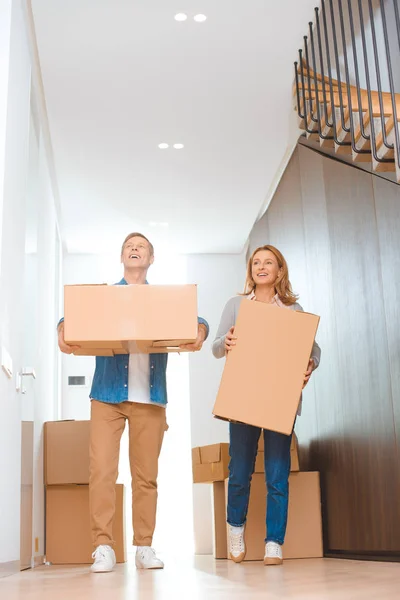 Casal feliz segurando caixas de papelão na nova casa — Fotografia de Stock