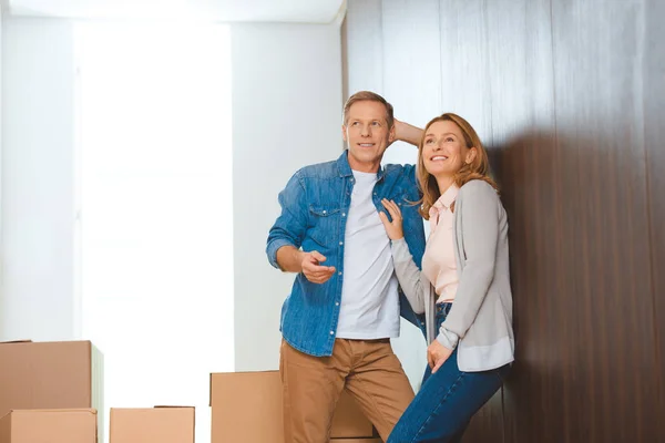 Heureux couple debout par mur près de boîtes en carton — Photo de stock