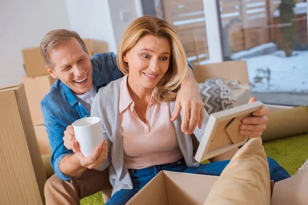 Cheerful couple unpacking cardboard box at new home — Stock Photo