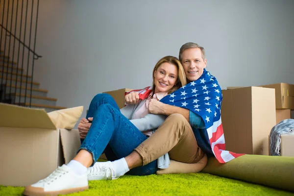 Felice coppia avvolgimento in USA bandiera nazionale e guardando la fotocamera — Foto stock