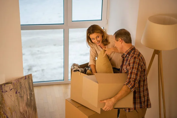 Marido sosteniendo caja de cartón mientras sonríe mujer desembalaje caja de cartón - foto de stock