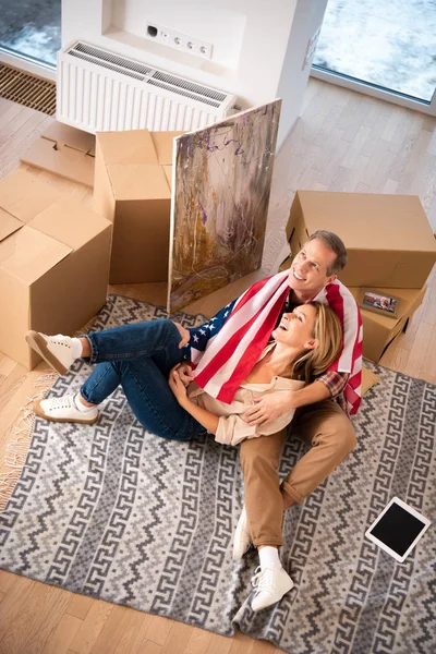 Happy smiling couple sitting on fleece blanket on floor at new home — Stock Photo