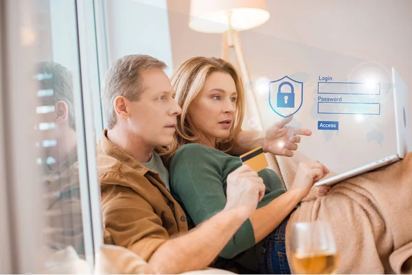Casal olhando para tela do laptop juntos enquanto marido segurando cartão de crédito, conceito de casa inteligente — Fotografia de Stock