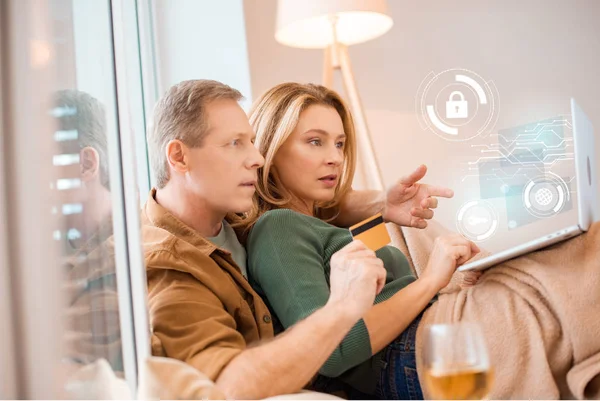 Pareja mirando a la pantalla del ordenador portátil juntos mientras marido celebración de la tarjeta de crédito, concepto de hogar inteligente - foto de stock