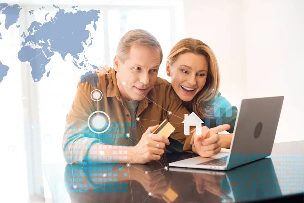 Coppia felice utilizzando computer portatile insieme mentre il marito in possesso di carta di credito, concetto di casa intelligente — Foto stock