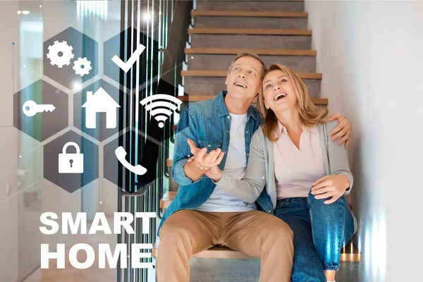 Marito e moglie felici seduti sulle scale nella nuova casa, concetto di casa intelligente — Foto stock