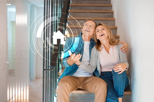 Couple excité assis sur les escaliers à la nouvelle maison, concept de maison intelligente — Photo de stock