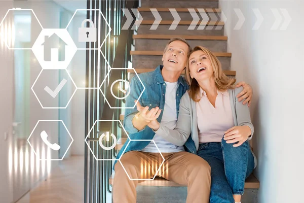 Inspired smiling couple sitting on stairs at new home, smart home concept — Stock Photo