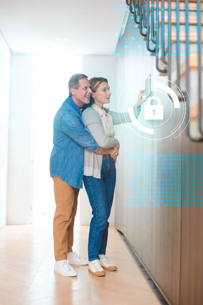 Husband hugging wife using smart house system control panel — Stock Photo