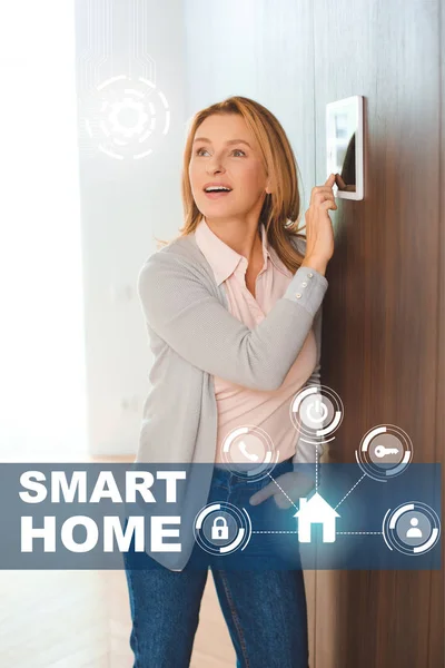Mulher inspirada feliz usando painel de controle da casa inteligente — Fotografia de Stock
