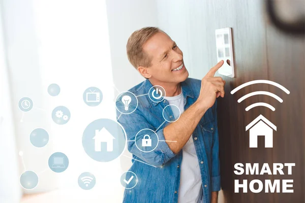 Hombre feliz utilizando el panel de control de la casa inteligente en el nuevo hogar - foto de stock