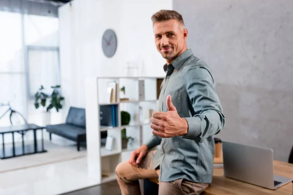 Feliz hombre de negocios mostrando el pulgar hacia arriba en la oficina moderna - foto de stock