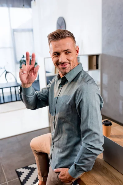 Cheerful businessman waving hand while smiling in modern office — Stock Photo