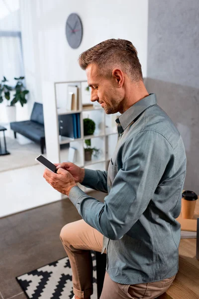 Happy businessman using smartphone in modern office — Stock Photo