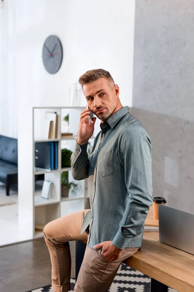 Seriöser Geschäftsmann spricht im modernen Büro auf dem Smartphone — Stockfoto