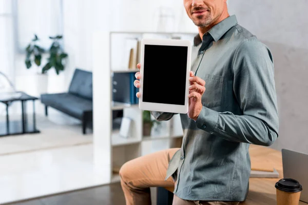 Vue recadrée de l'homme d'affaires heureux tenant tablette numérique avec écran blanc dans le bureau moderne — Photo de stock