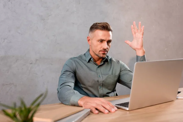 Homme d'affaires émotionnel gestuelle tout en utilisant un ordinateur portable dans le bureau moderne — Photo de stock