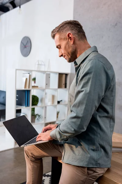 Сфокусированный бизнесмен с помощью ноутбука с чистым экраном в офисе — стоковое фото