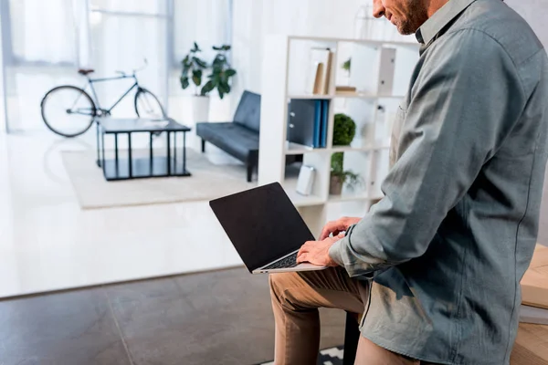 Vista recortada del hombre de negocios utilizando el ordenador portátil con pantalla en blanco en la oficina - foto de stock
