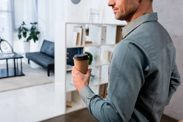 Cropped view of businessman holding paper cup with drink in office — Stock Photo