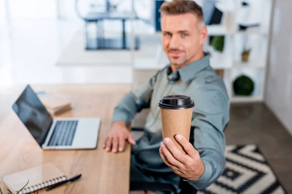 Selective focus of paper cup in hand of cheerful businessman in office — Stock Photo