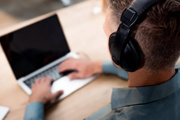 Messa a fuoco selettiva di uomo d'affari ascoltare musica in cuffie durante l'utilizzo di laptop — Foto stock