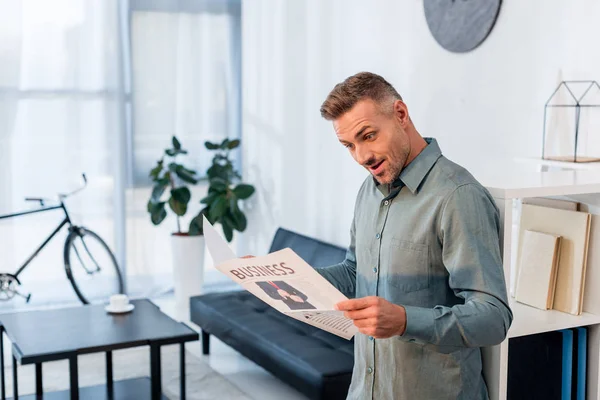 Удивленный бизнесмен читает деловую газету в современном офисе — стоковое фото