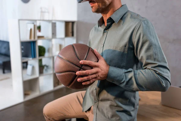 Cropped view of businessman holding basketball in office — Stock Photo