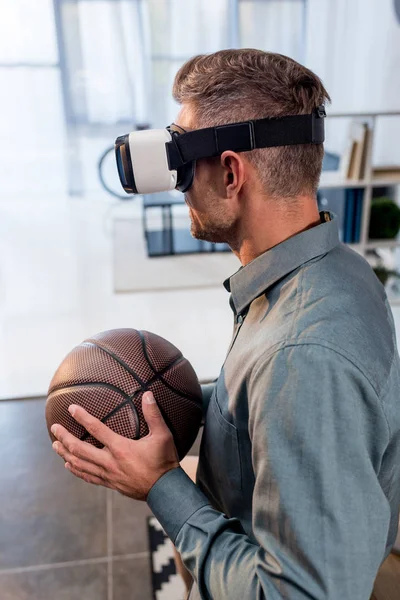 Uomo d'affari indossando auricolare realtà virtuale e tenendo basket — Foto stock