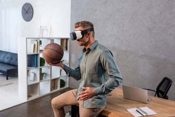 Uomo d'affari indossando auricolare realtà virtuale e tenendo il basket in ufficio moderno — Foto stock