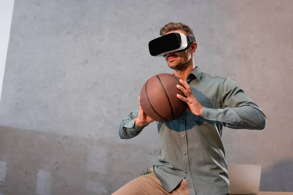 Uomo d'affari in realtà virtuale auricolare in possesso di basket in ufficio — Foto stock