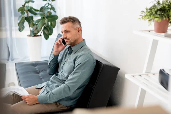 Selective focus of handsome businessman talking on smartphone while sitting on sofa — Stock Photo