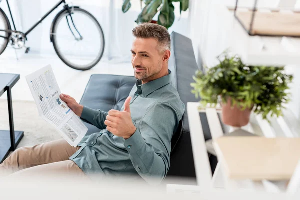 Selective focus of cheerful businessman holding newspaper and showing thumb up — Stock Photo